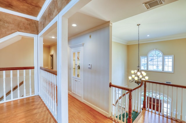 hallway featuring crown molding, visible vents, an upstairs landing, wood finished floors, and a chandelier