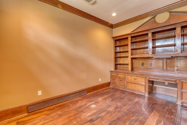 unfurnished office featuring dark wood-style floors, visible vents, crown molding, and built in desk