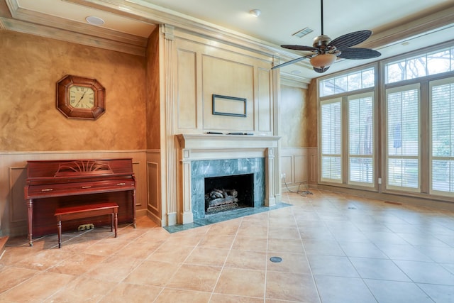 living area featuring light tile patterned floors, visible vents, ornamental molding, a decorative wall, and a high end fireplace