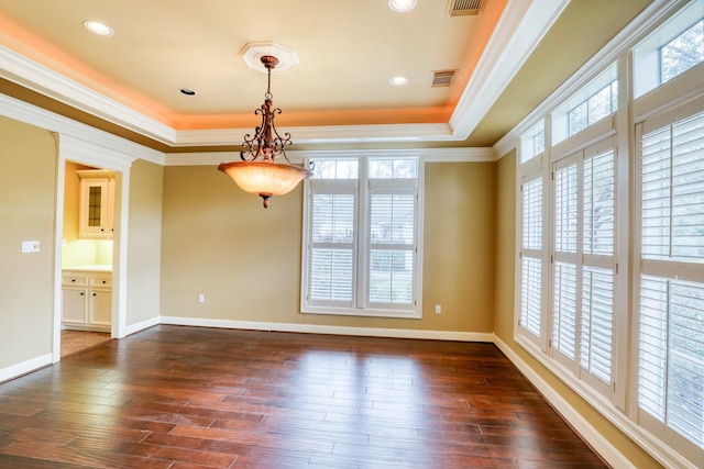 empty room with visible vents, a raised ceiling, ornamental molding, dark wood-type flooring, and a wealth of natural light