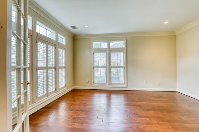 empty room featuring visible vents, baseboards, wood finished floors, crown molding, and recessed lighting