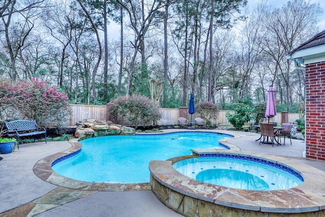 view of swimming pool with outdoor dining area, a pool with connected hot tub, a patio area, and a fenced backyard