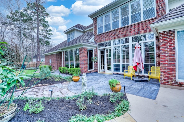 rear view of house featuring brick siding and a patio area