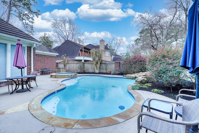 view of pool with a pool with connected hot tub, fence, and a patio