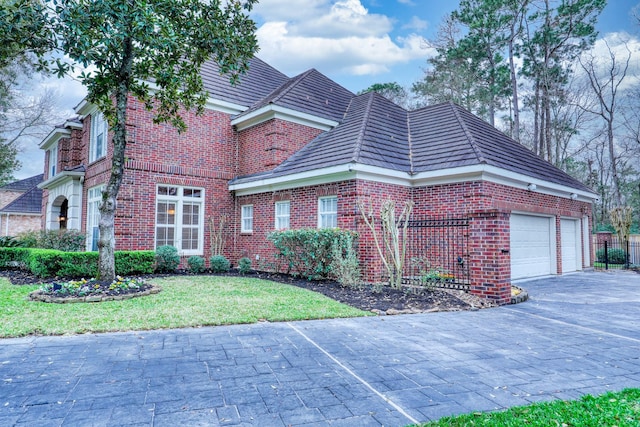 view of front facade with driveway, brick siding, a front lawn, and an attached garage