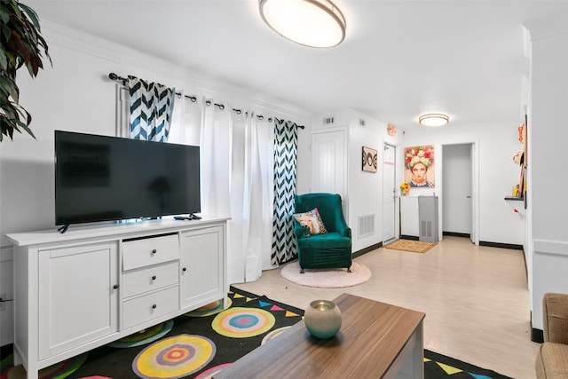 living room featuring visible vents, crown molding, baseboards, and wood finished floors