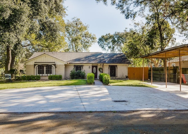 ranch-style house with a front yard, concrete driveway, and fence