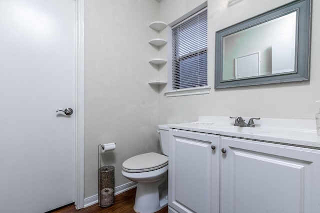 bathroom featuring baseboards, vanity, toilet, and wood finished floors