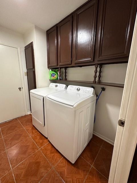 clothes washing area with cabinet space, washing machine and dryer, and light tile patterned floors