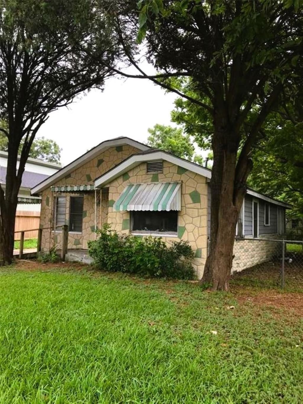 view of front facade featuring stone siding, fence, and a front lawn