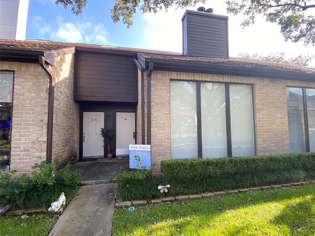 property entrance featuring brick siding and a chimney