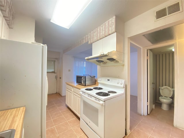 kitchen featuring white appliances, light tile patterned floors, visible vents, and light countertops