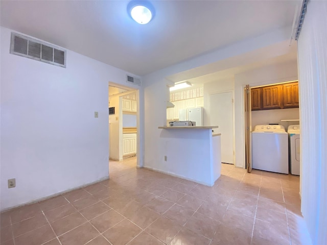 kitchen featuring freestanding refrigerator, separate washer and dryer, a peninsula, and visible vents