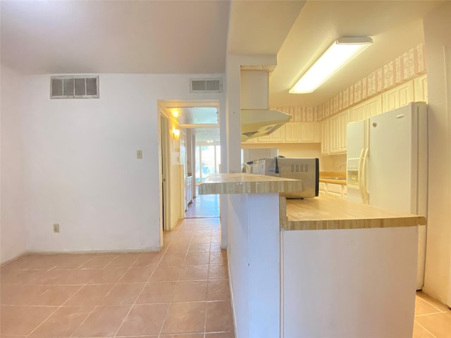 kitchen featuring white fridge with ice dispenser, visible vents, ventilation hood, and light tile patterned floors