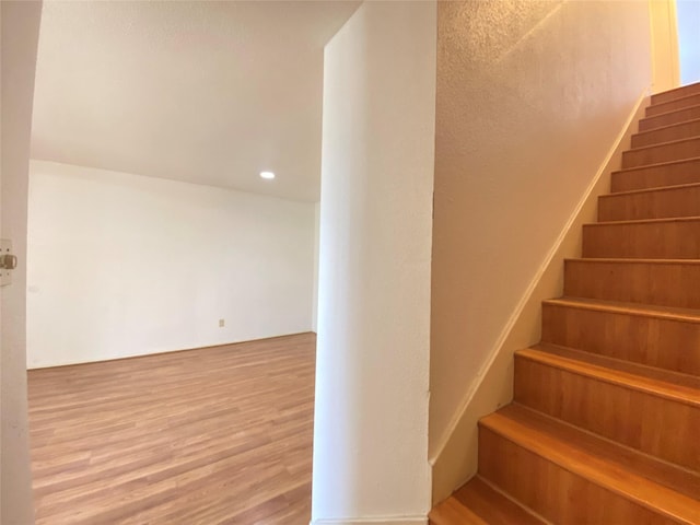 stairway featuring wood finished floors and recessed lighting