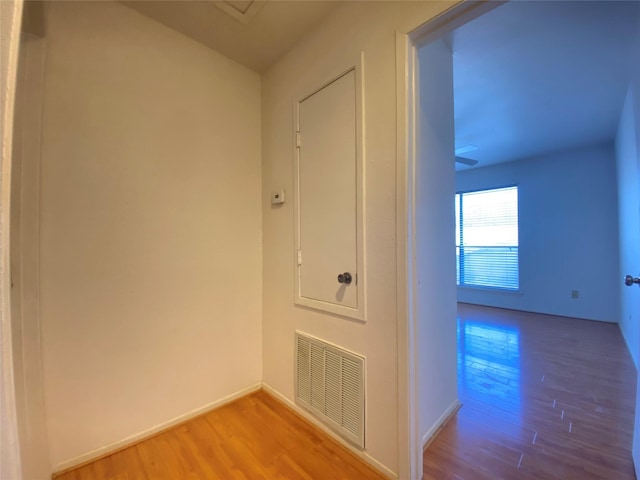 corridor featuring wood finished floors, visible vents, and baseboards