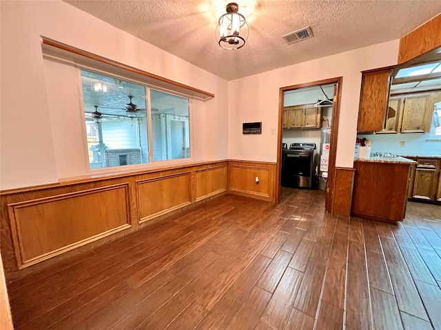 kitchen with visible vents, brown cabinets, dark wood-type flooring, and a wainscoted wall