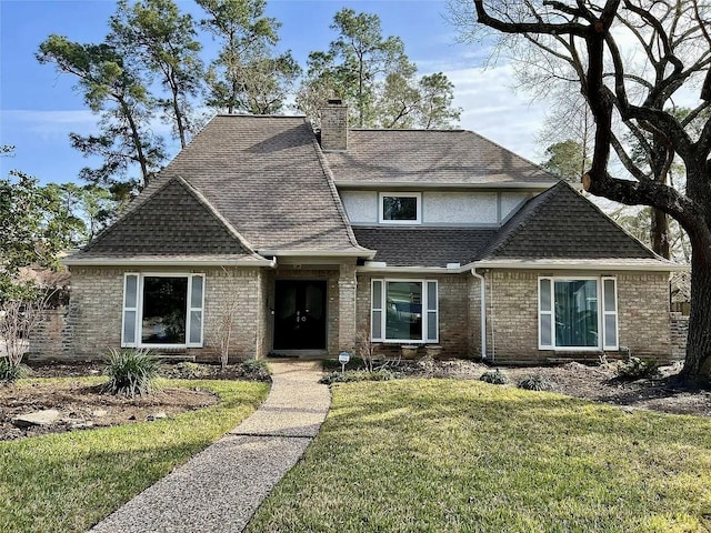 view of front facade with stucco siding, a chimney, a front lawn, and a shingled roof