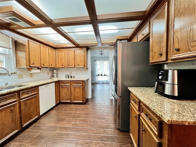 kitchen featuring wood finish floors, visible vents, brown cabinets, a sink, and dishwasher