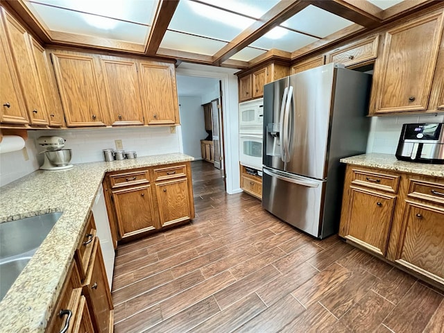 kitchen with decorative backsplash, white appliances, and brown cabinetry