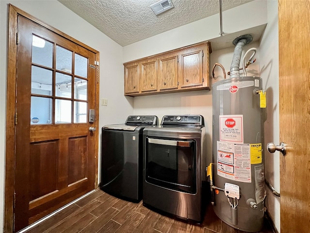 laundry area with washing machine and clothes dryer, visible vents, dark wood finished floors, gas water heater, and cabinet space