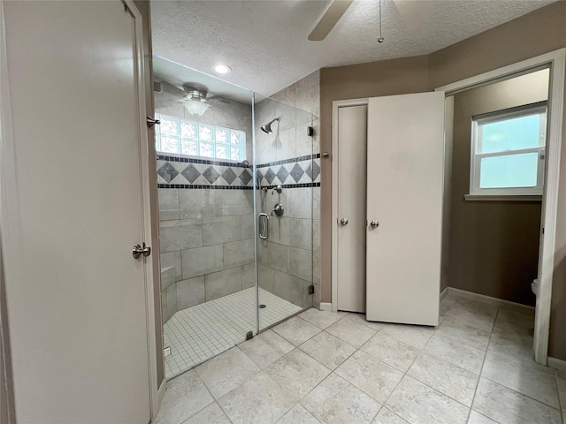 full bath featuring baseboards, a ceiling fan, a stall shower, and a textured ceiling