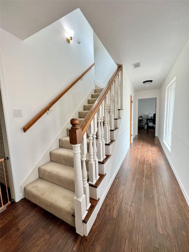 stairs with wood finished floors, visible vents, and baseboards