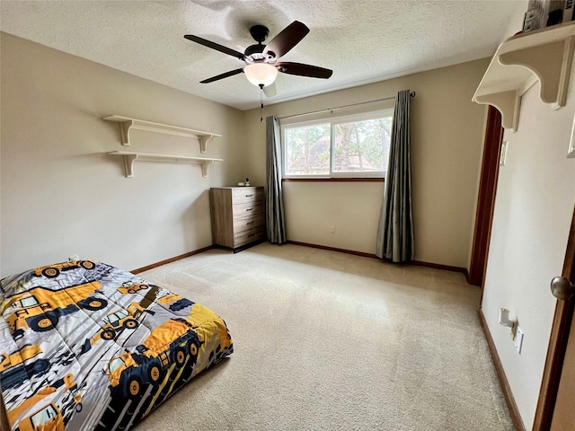 unfurnished bedroom featuring light colored carpet, baseboards, a textured ceiling, and a ceiling fan