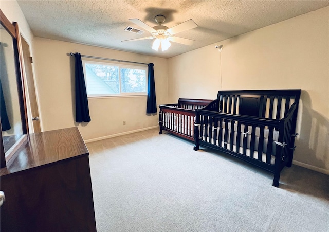 carpeted bedroom with visible vents, baseboards, a textured ceiling, and a ceiling fan