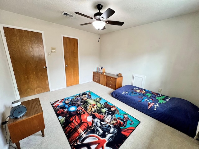 carpeted bedroom with baseboards, visible vents, a textured ceiling, and a ceiling fan