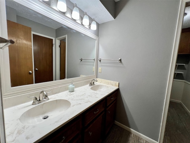 bathroom with a sink, baseboards, and double vanity