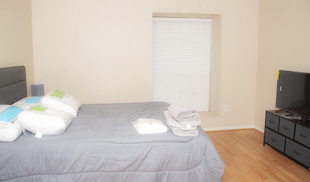 bedroom with light wood finished floors and baseboards