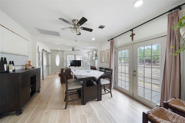 dining space featuring a barn door, visible vents, light wood-style flooring, and a wealth of natural light