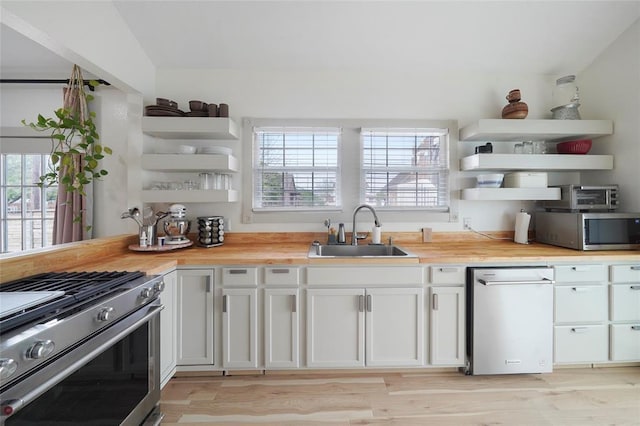 kitchen featuring butcher block countertops, a sink, white cabinetry, appliances with stainless steel finishes, and open shelves