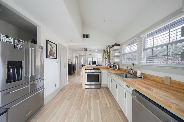 kitchen featuring stainless steel appliances, butcher block counters, visible vents, white cabinets, and a sink