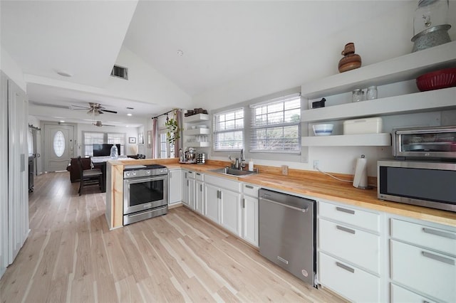 kitchen featuring butcher block countertops, a sink, white cabinets, appliances with stainless steel finishes, and open shelves