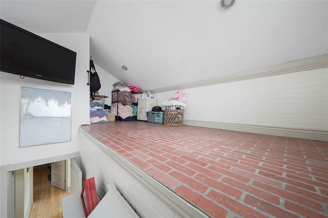 bonus room with lofted ceiling and brick floor