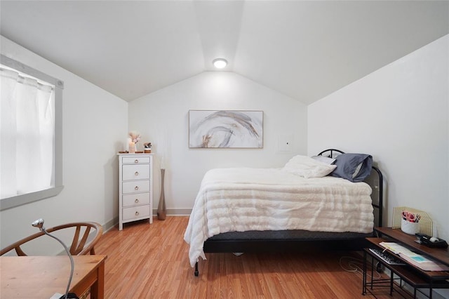 bedroom with lofted ceiling, baseboards, and light wood-style floors