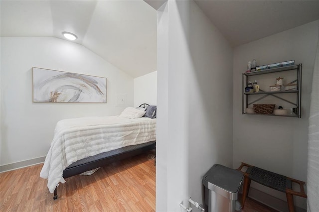 bedroom featuring lofted ceiling, baseboards, and wood finished floors