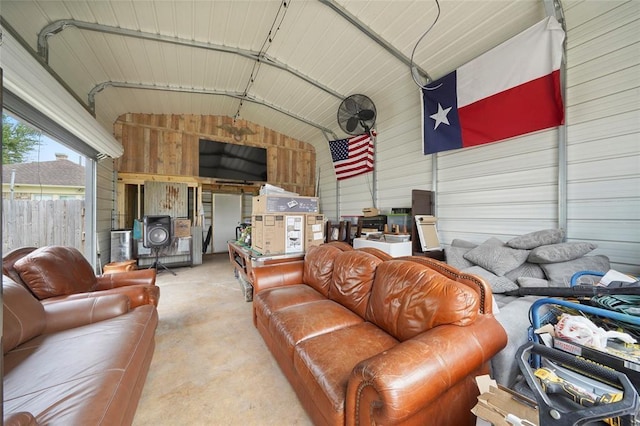 living area with a garage, metal wall, vaulted ceiling, and concrete flooring