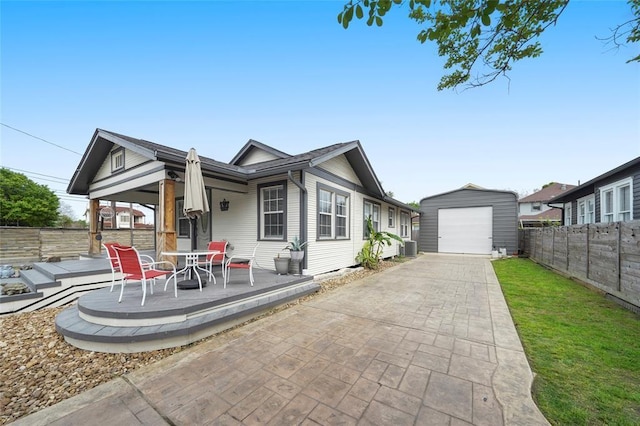 view of front of home featuring a patio, a fenced backyard, an outdoor structure, a detached garage, and concrete driveway