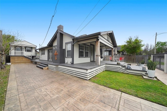 view of front of house with a patio, fence, a wooden deck, a chimney, and a front yard