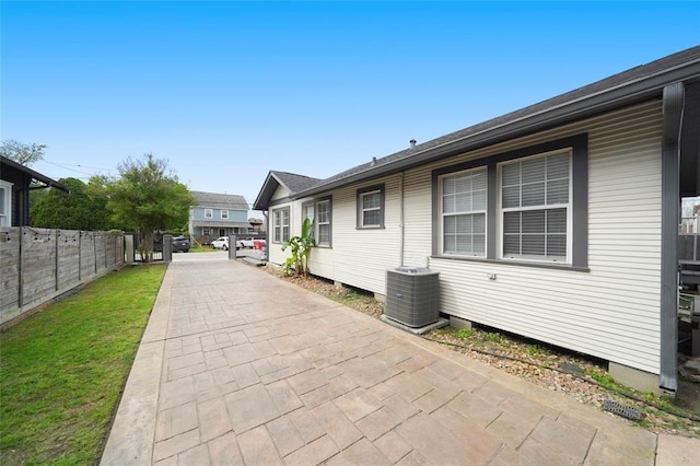 view of side of property featuring fence and central AC