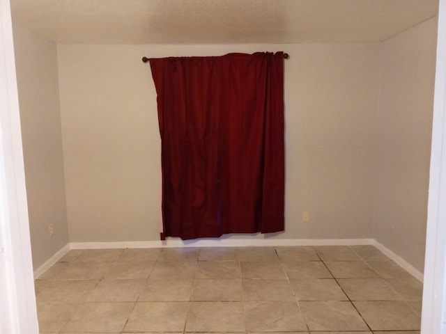 spare room with light tile patterned flooring and baseboards