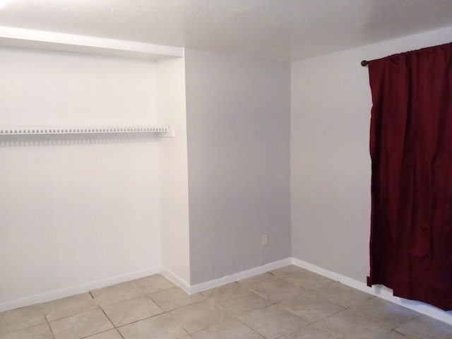 spare room featuring light tile patterned floors and baseboards