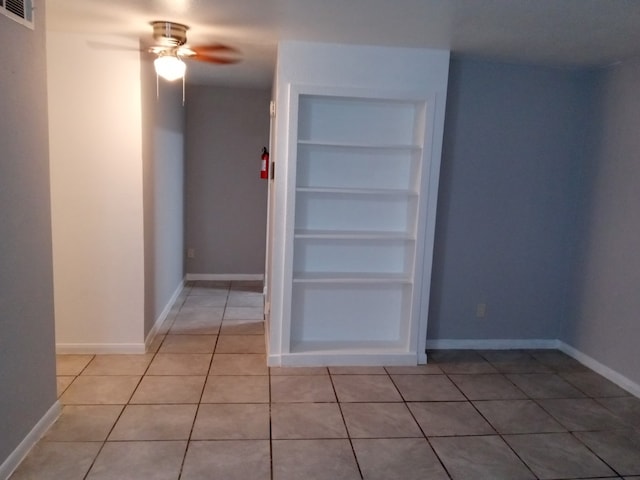 unfurnished room featuring baseboards, visible vents, a ceiling fan, built in features, and light tile patterned flooring