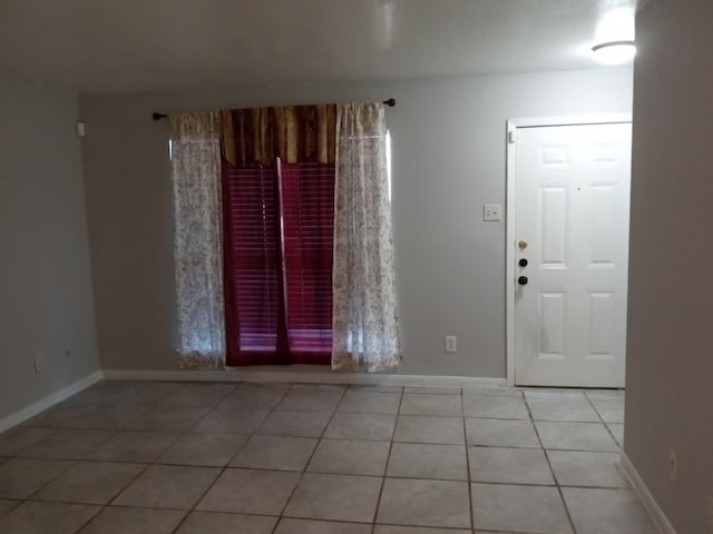 unfurnished room with light tile patterned floors and baseboards