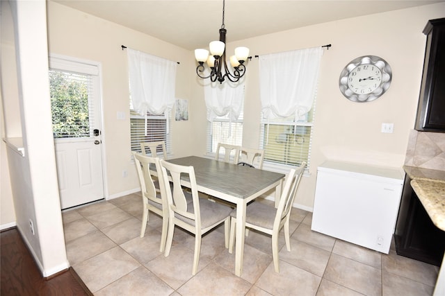 dining area featuring baseboards, light tile patterned floors, and an inviting chandelier