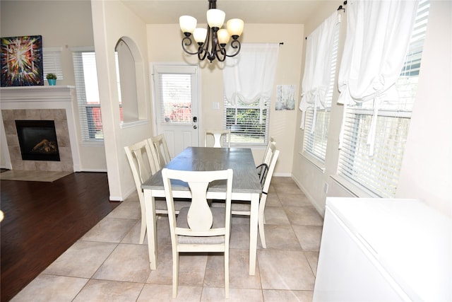 dining space with an inviting chandelier, baseboards, a tiled fireplace, and light tile patterned flooring