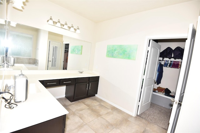 full bath featuring a garden tub, a sink, baseboards, double vanity, and a walk in closet